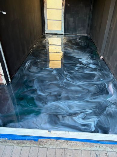 Shiny black and white swirled epoxy floor in a narrow room.