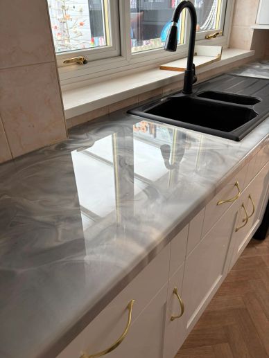 Modern kitchen countertop with black sink and gold handles.