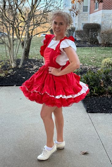 Woman in vibrant red and white dress posing outdoors.