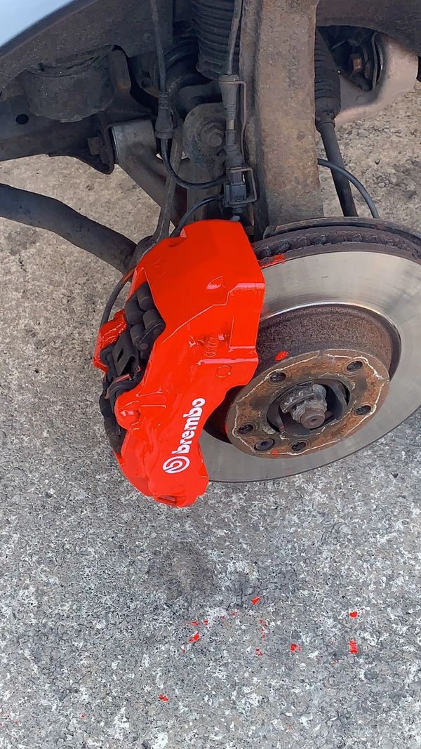 Close-up of a car's brake system with a bright red Brembo caliper.