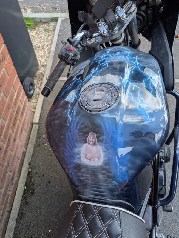 Custom motorcycle gas tank with lightning and angel wings design.
