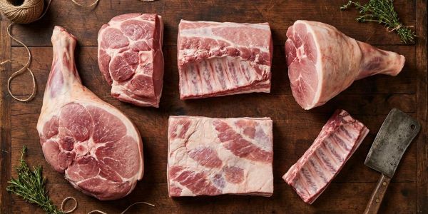 Various cuts of raw pork displayed on a wooden surface.
