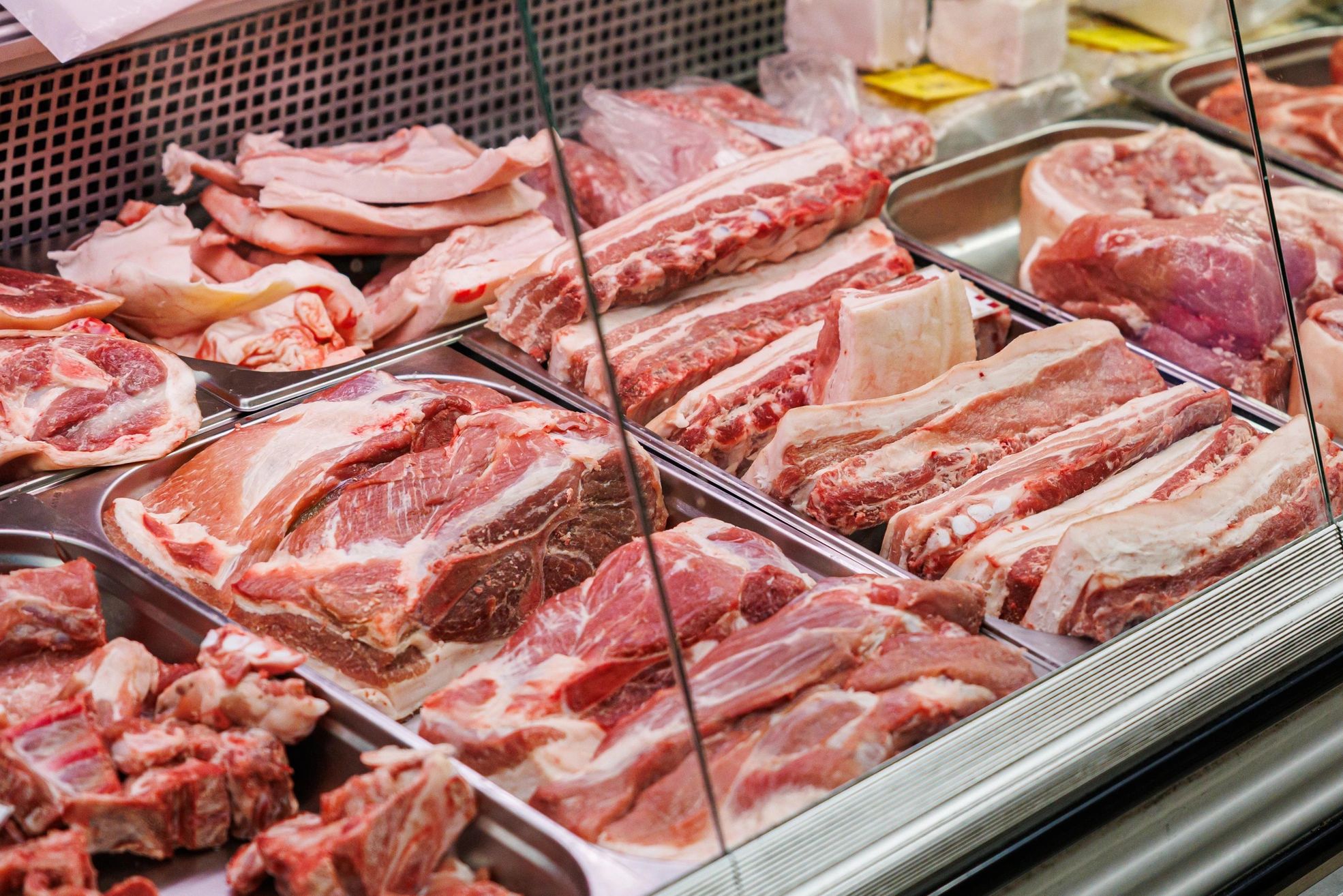 Various cuts of fresh raw pork displayed in a butcher shop.