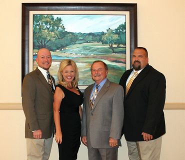 Group of four people posing formally indoors.