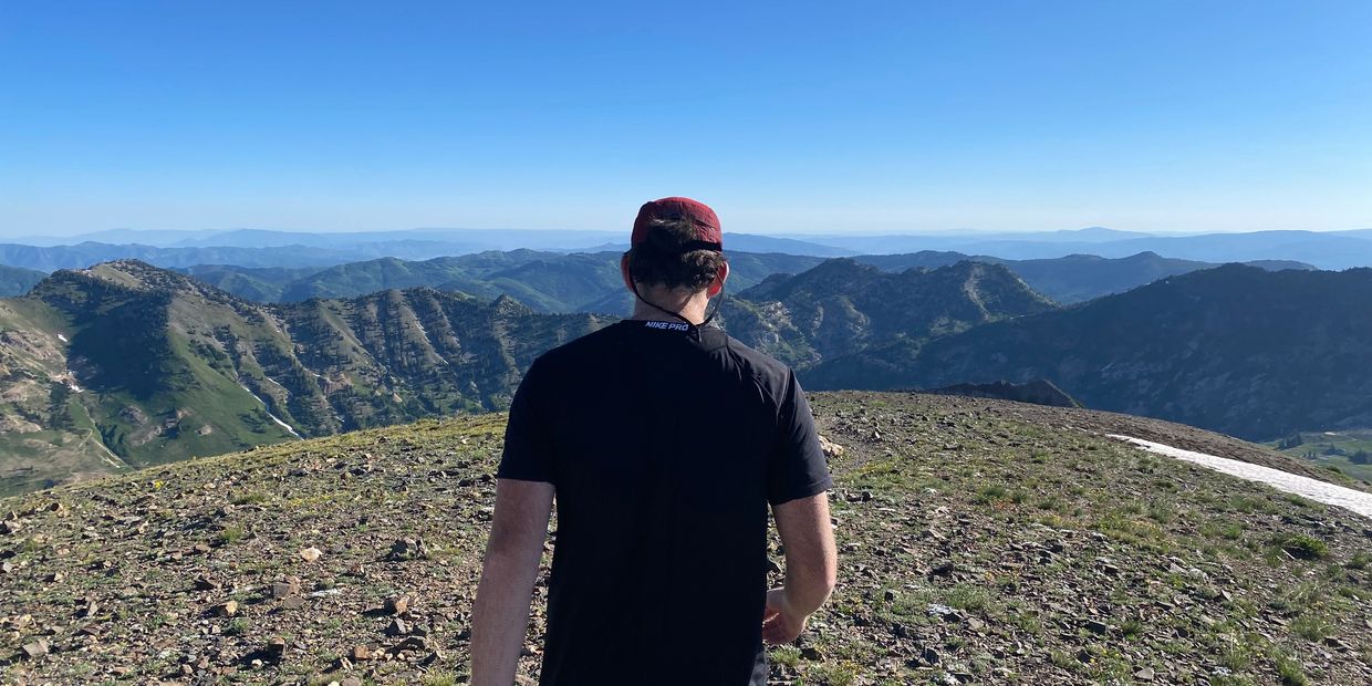 Mark Wilkes on top of a hill facing a vast mountain range