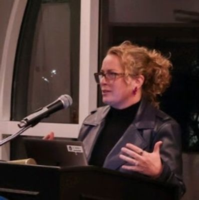 Woman speaking at a podium with a microphone and laptop.