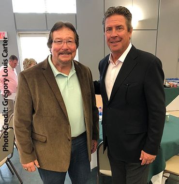 Two men posing indoors, both smiling.