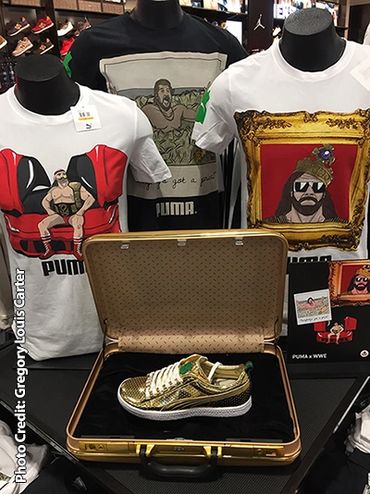Gold sneaker in a case with graphic PUMA t-shirts behind.