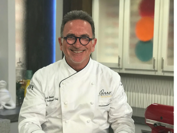 Chef presenting a beautifully browned meringue dessert in a modern kitchen.