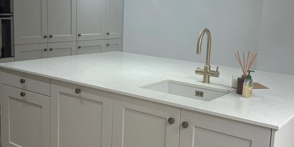 Modern white kitchen island with a sink and faucet.
