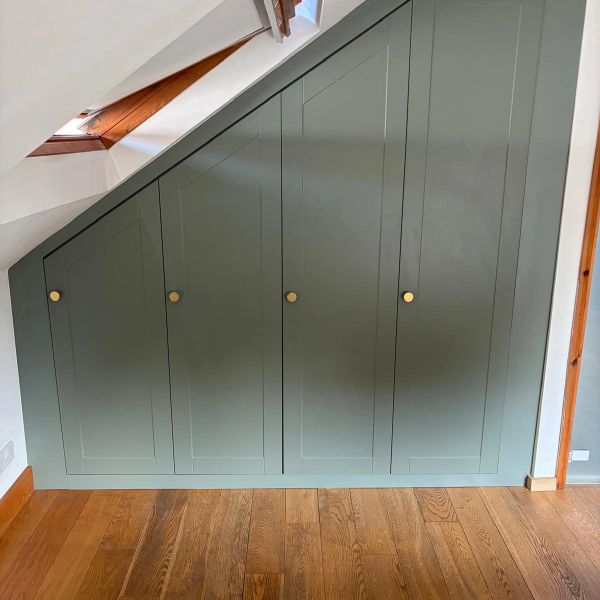 Green under-stairs cupboard with four doors.