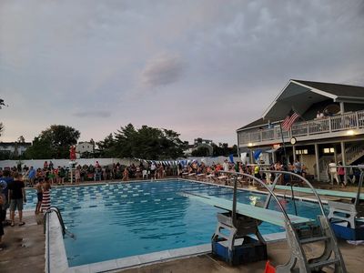 Community gathering around an outdoor pool at dusk.