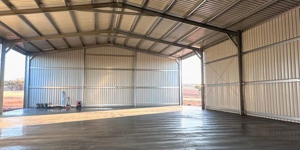 Empty metal shed with concrete floor and corrugated walls under a metal roof.