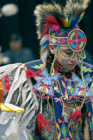 Native American dancer in colorful traditional regalia with feathers and beadwork.