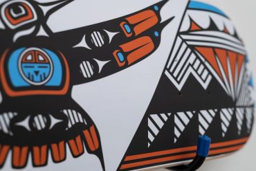 Close-up of a black, white, orange, and blue Indigenous-style artwork.