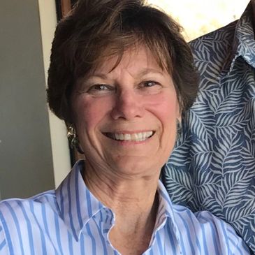 Smiling woman in a striped shirt, standing next to someone.