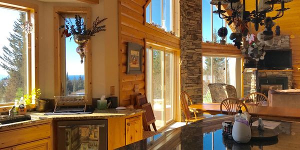 Cozy wooden cabin kitchen and dining area with large windows and natural light.
