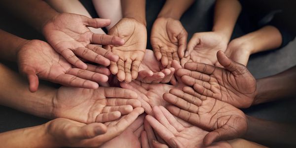 Diverse hands joined together in a circle symbolizing unity and support.