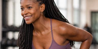 A smiling woman with braided hair in workout attire.