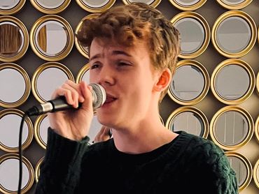 A young man singing into a microphone in a cozy living room.