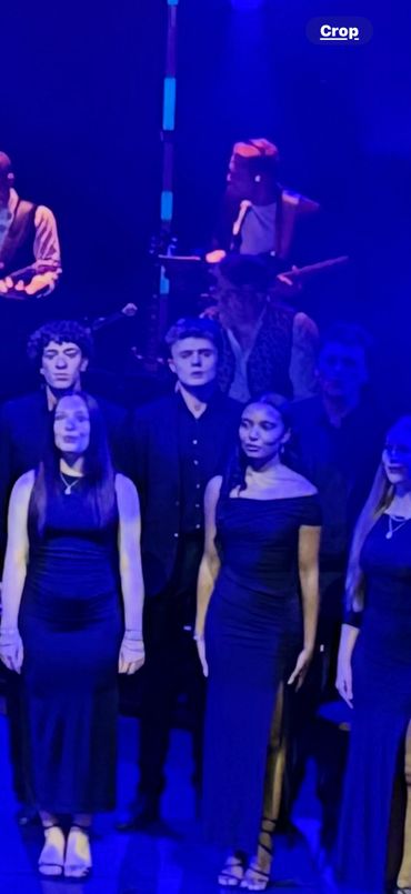 Group of performers singing on stage under blue lighting.