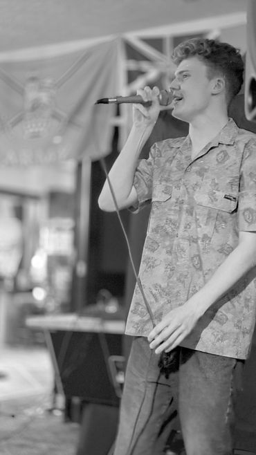 Young man singing on stage with a microphone.