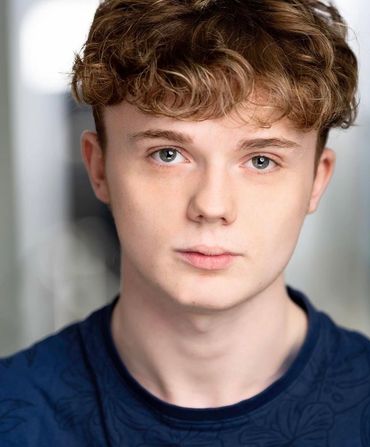 Close-up portrait of a young man with curly hair and blue eyes.