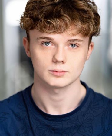 Close-up portrait of a young man with curly hair and blue eyes.