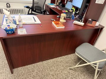 A tidy office desk with a folding chair and various items organized on top.