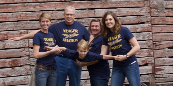 family of 5 holding young child up like an airplane and posing for a family photo. 