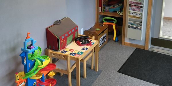 Office waiting room children toy area, small table with two chairs and assortment of toys. 