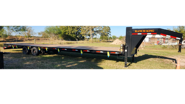 Large Ranch King flatbed trailer parked on grass in a rural area.