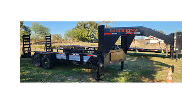Black Ranch King gooseneck trailer parked on grass with ramps.