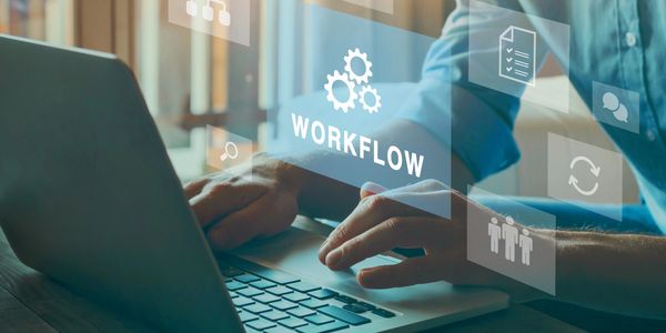 Person working on laptop with digital workflow icons floating above.