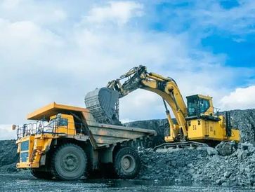 Excavator loading a dump truck at a mining site.