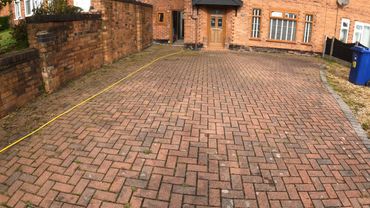 a dirty block paving driveway covered in weeds and moss, ready for cleaning