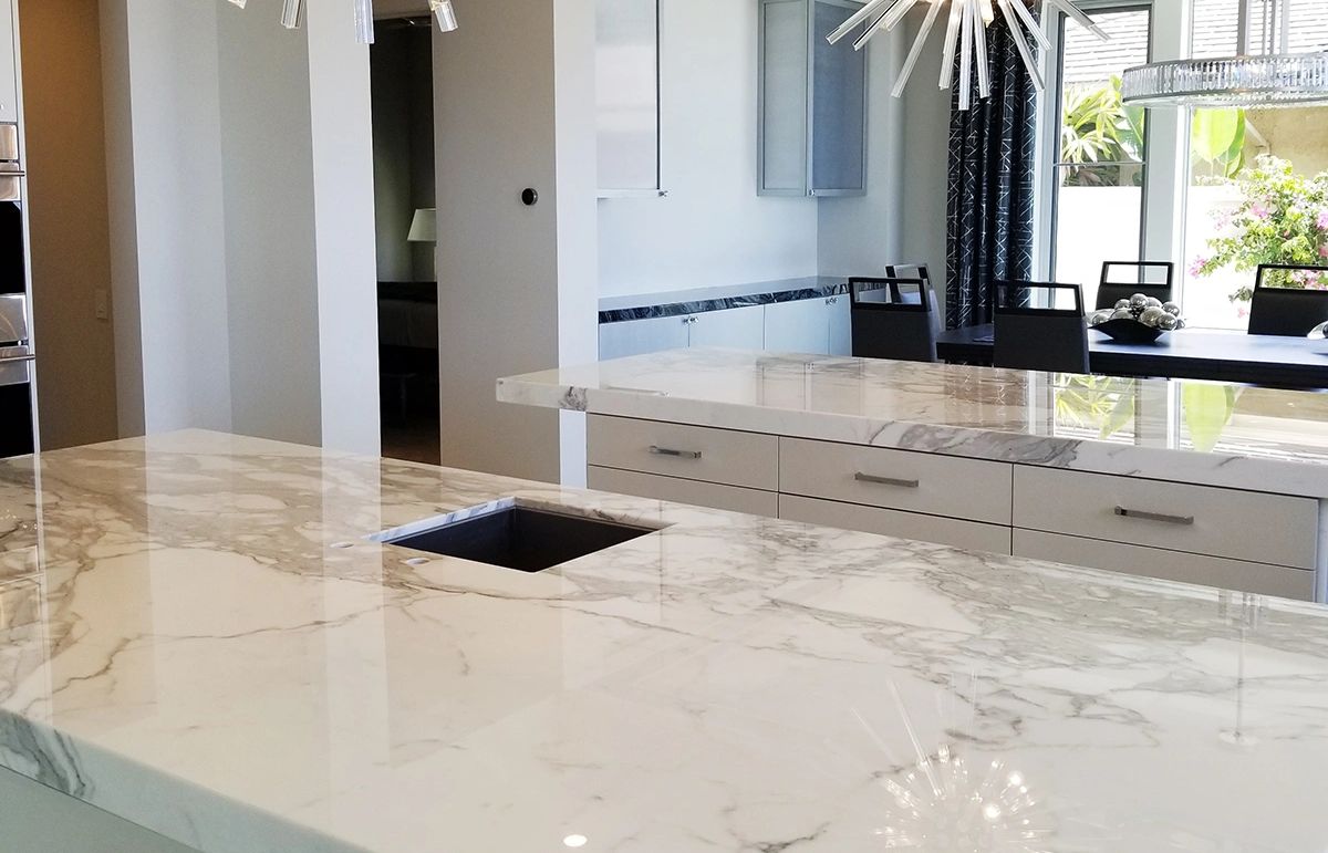 Modern kitchen with marble countertops and dining area.