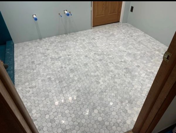 Newly tiled bathroom floor with white hexagonal tiles.