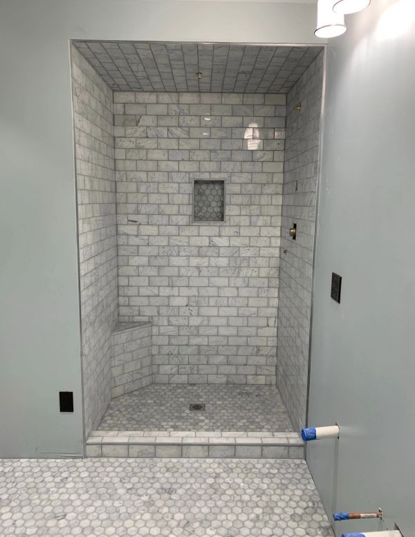 Marble-tiled shower area with built-in seat and niche.