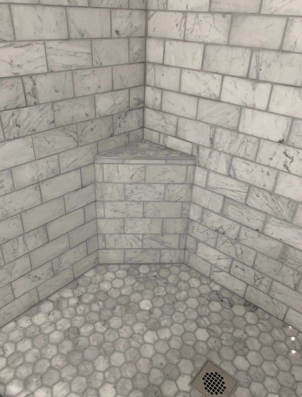 Corner bench in a marble-tiled shower.