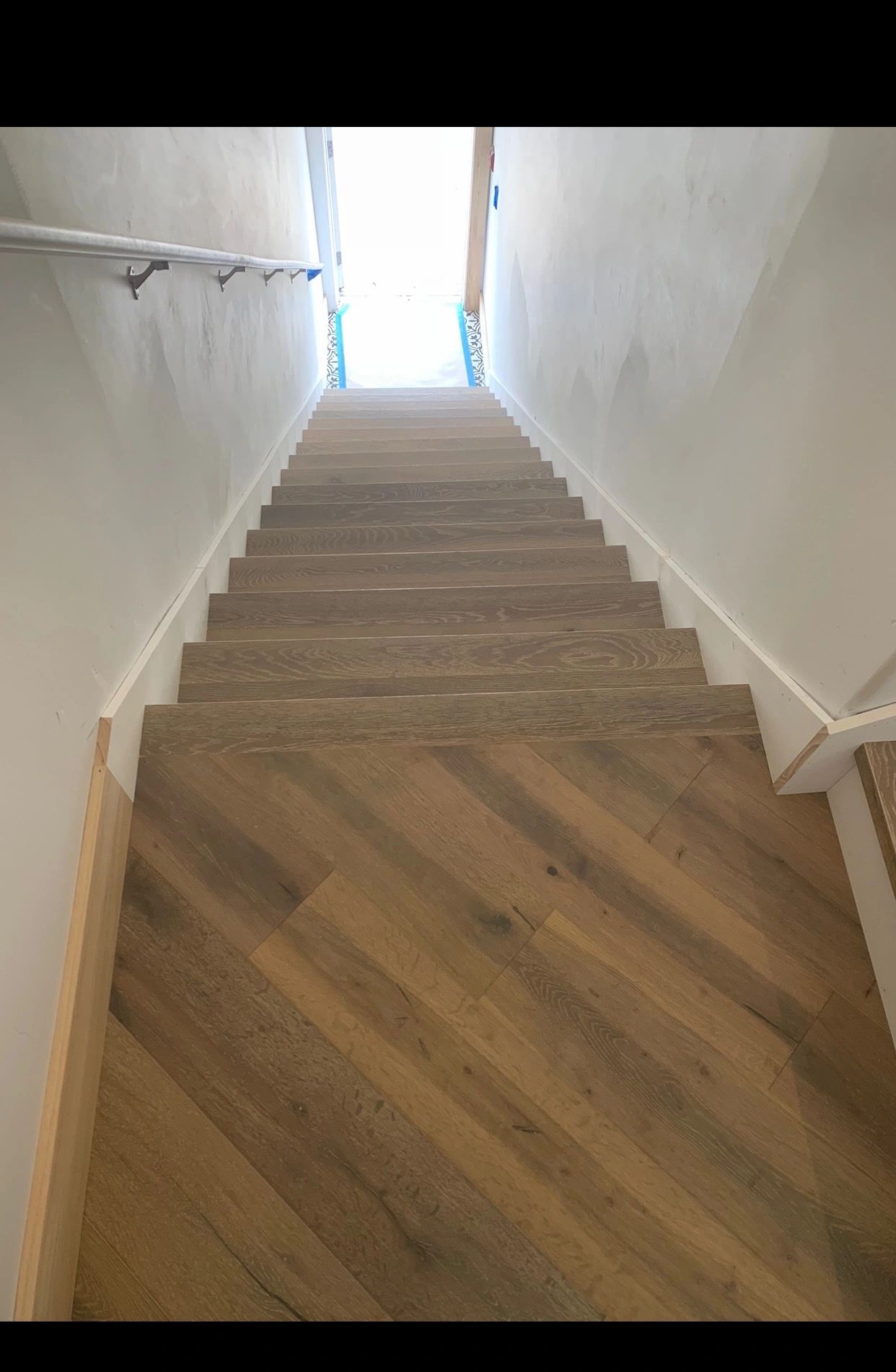 Wooden stairs leading down to a bright exit.