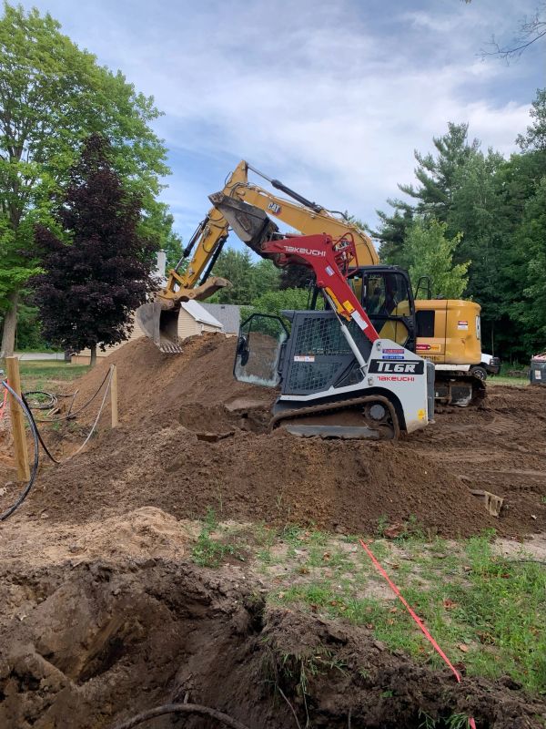Excavators working on a construction site with dirt piles.