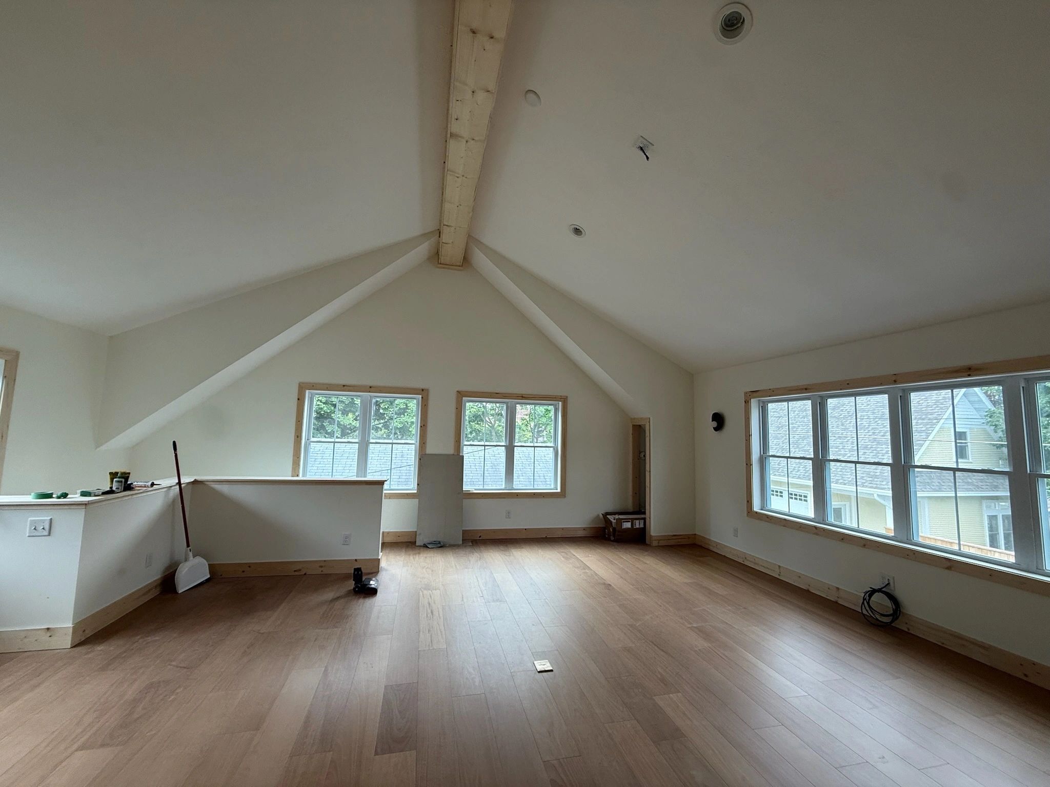 Empty room with wooden floors and large windows.