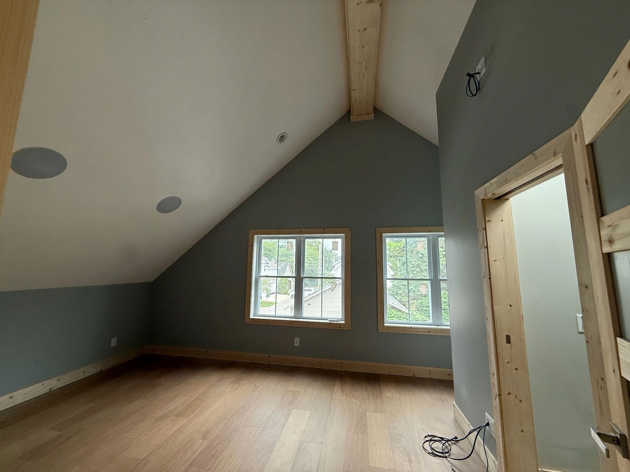 Empty room with sloped ceiling and two windows.