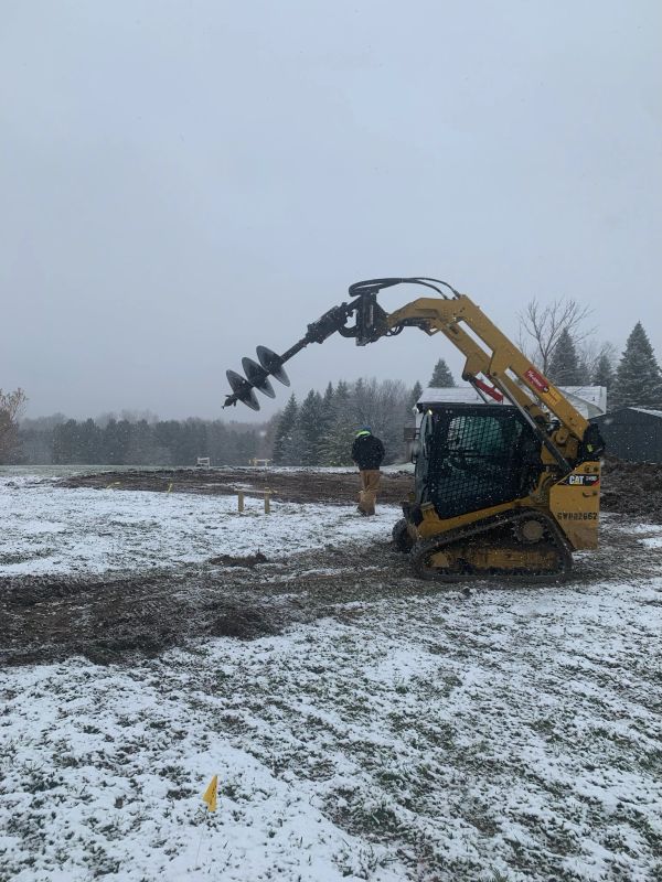 Construction worker with machinery on snowy ground.