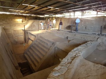 Ancient stepped pyramid structure with visitors exploring the site indoors.