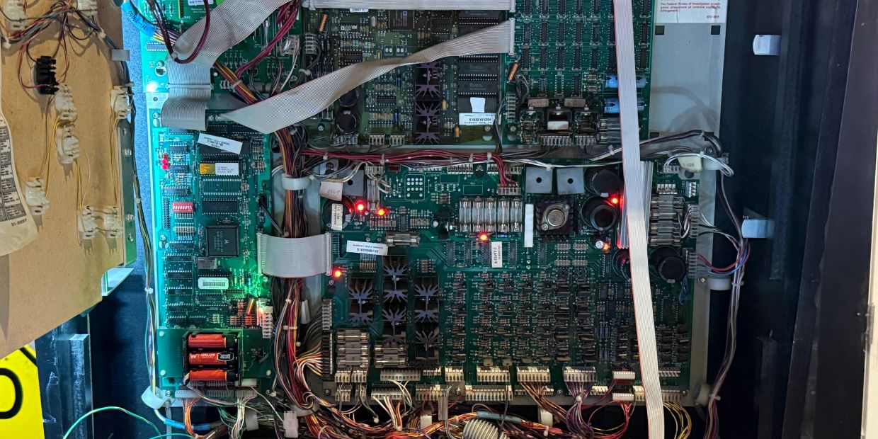 Open electronic circuit board with lit indicator lights and wiring.