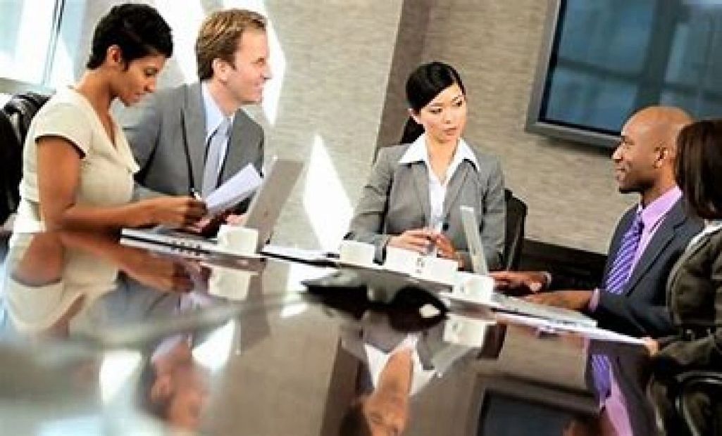 Boardroom with 5 people sitting around a conference room table