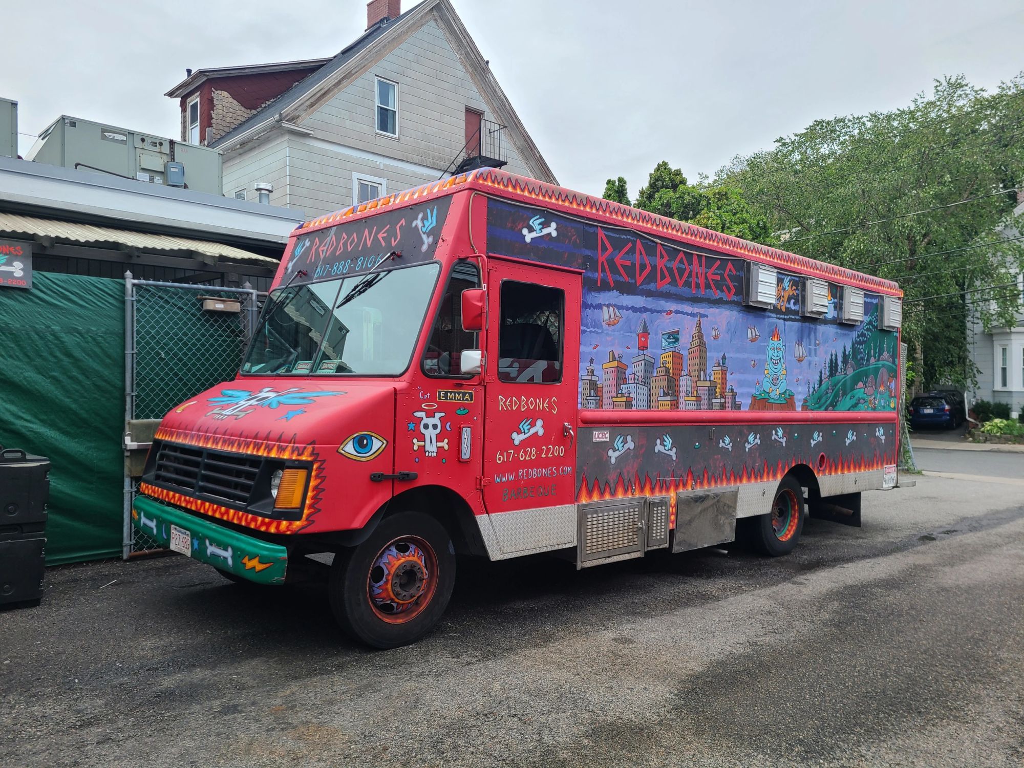 The Redbones food truck: a red step-van painted with the flame wordmark, a Somerville skyline mural, winged bones and flames, parked on a side street
