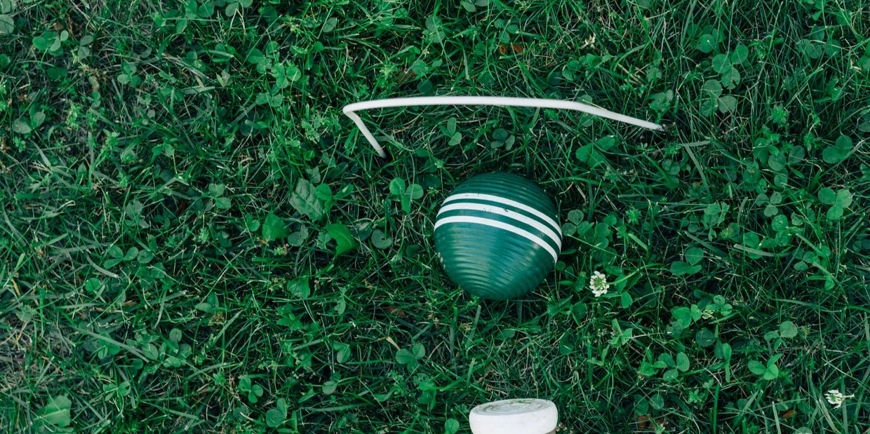 A croquet mallet and balls on green grass, ready for play.